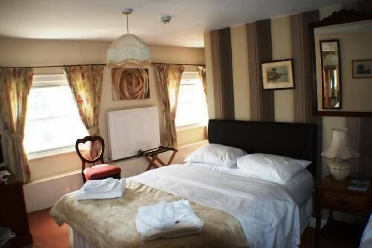 Una camera d'albergo con un letto, una sedia, una scrivania e un termosifone.