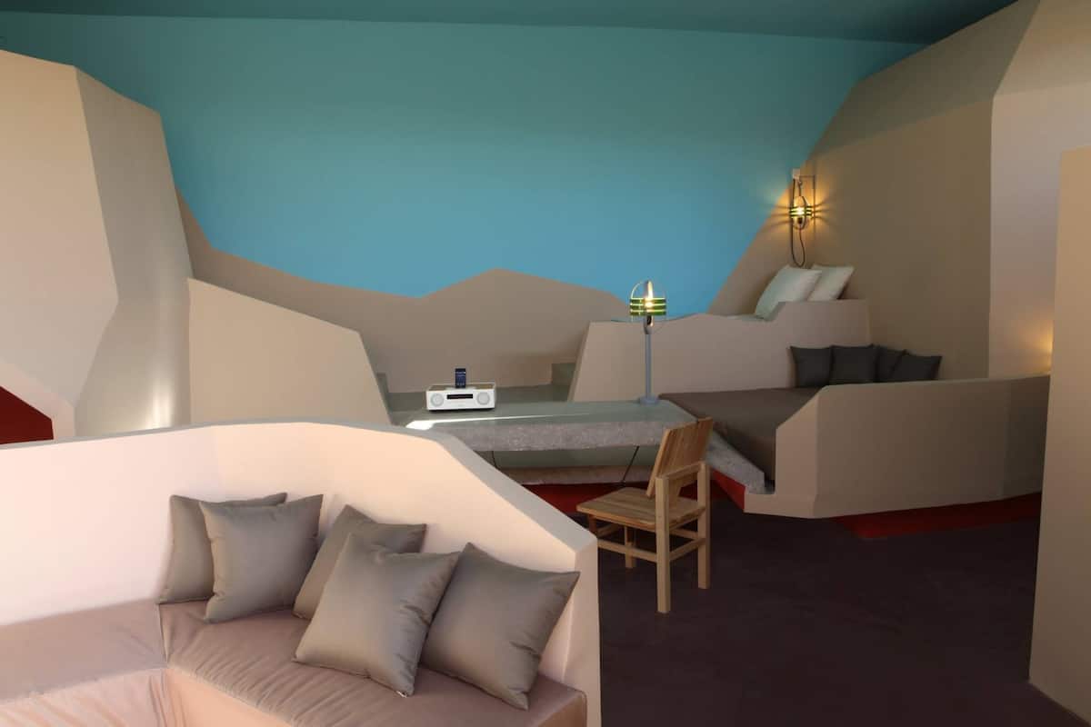 Ein modernes Zimmer mit einem einzigartigen geometrischen Design, einem bequemen Sofa, einem Sessel und einem Schreibtisch mit einem Radio.