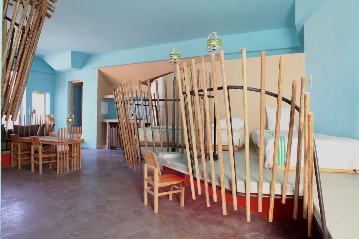 Ein Zimmer mit einem gewölbten Bett, einem Holztisch mit Stühlen und einem roten Teppich.