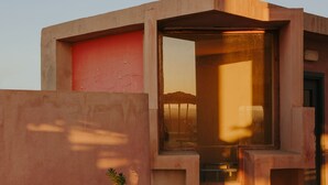 A modern building with a concrete exterior, a potted cactus, and a staircase leading to an entrance. - Dar Hi (Nefta)