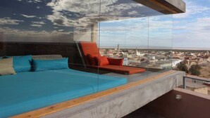 A modern room with a glass wall overlooking a cityscape. - Dar Hi (Nefta)