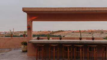 An outdoor bar area with a concrete countertop and wooden stools.