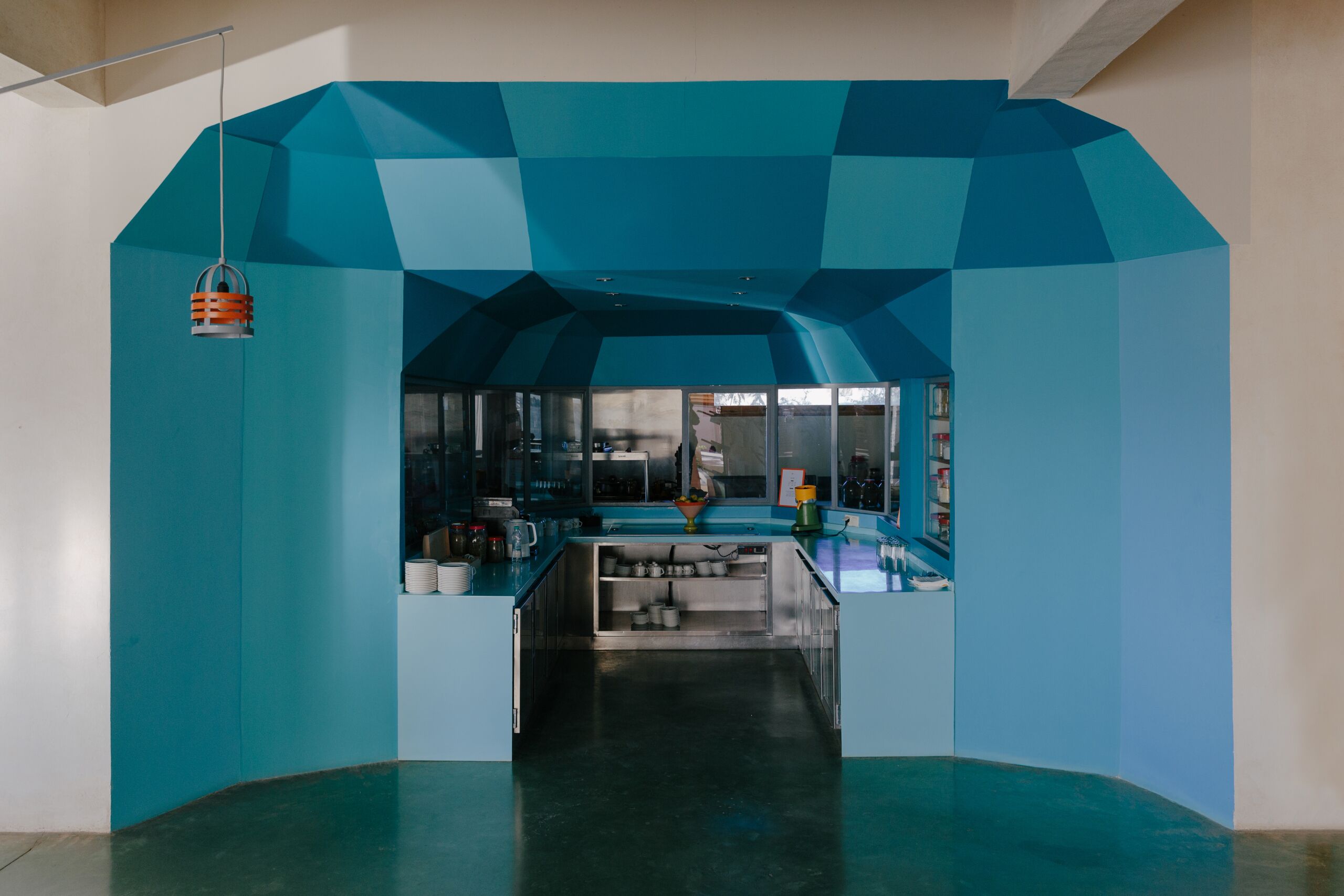 Uma cozinha moderna com design geométrico no teto, eletrodomésticos de aço inoxidável e uma ilha central.