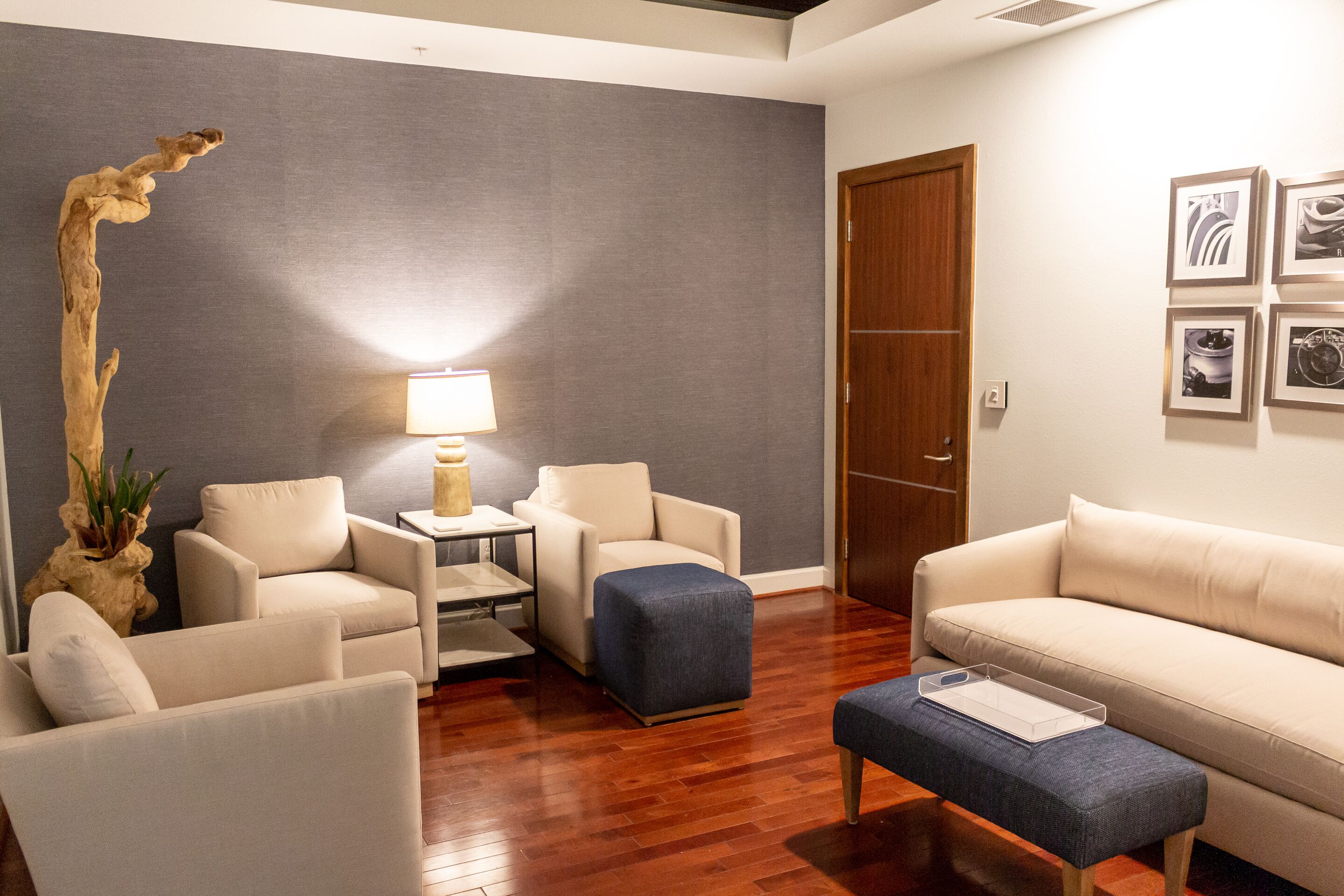 A modern living room with a sofa, armchairs, a coffee table, and a lamp.