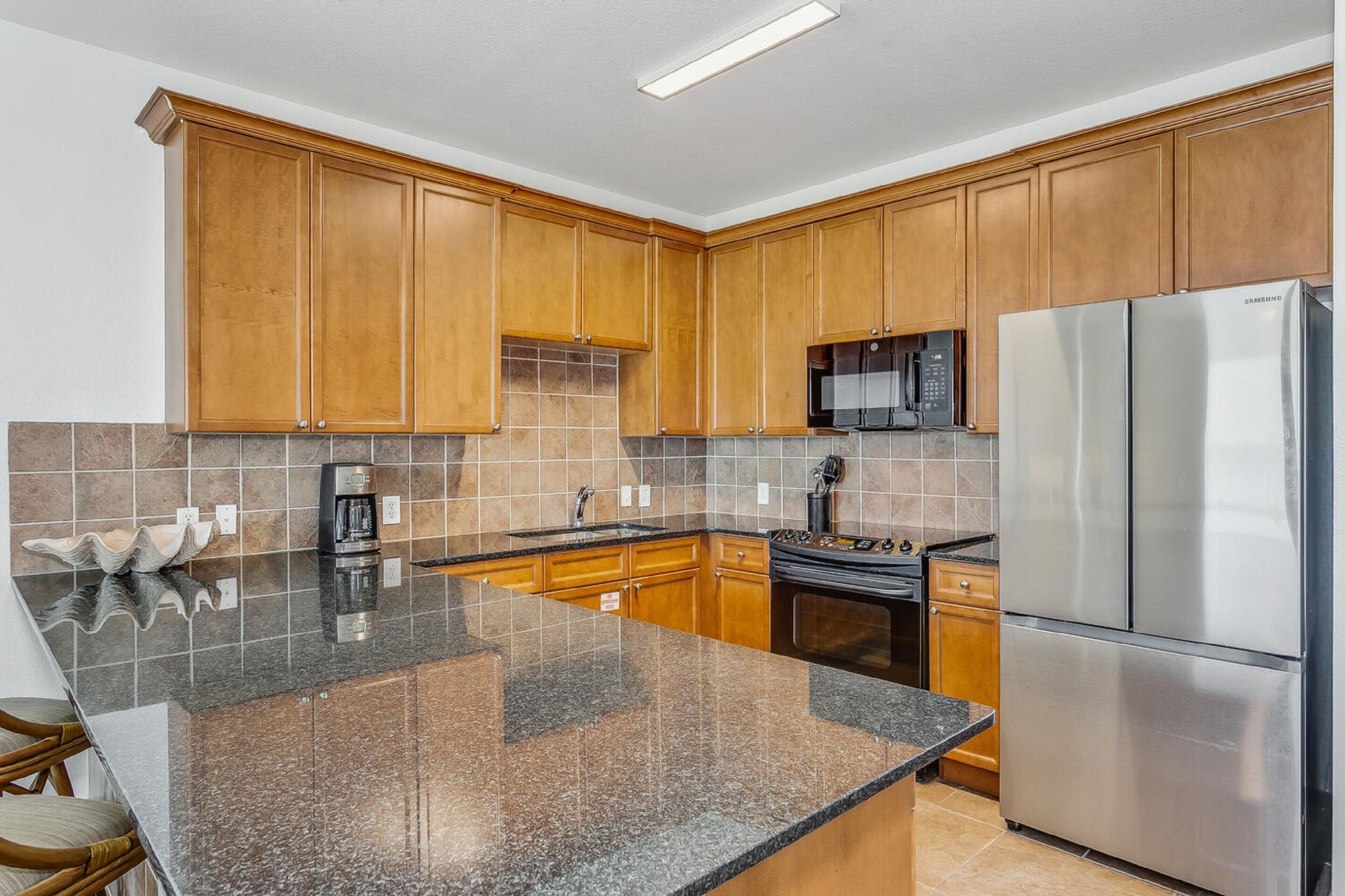 A kitchen with wooden cabinets, a stainless steel refrigerator, a microwave, and a coffee maker.