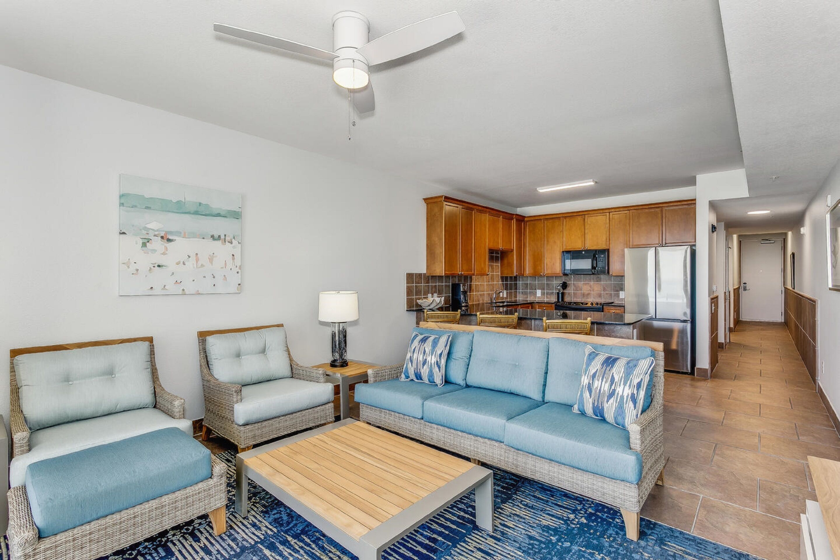 A modern living room with wicker furniture, a blue sofa, and a wooden coffee table.