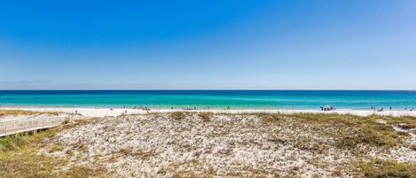 A beach with a sandy foreground and a clear blue sky.