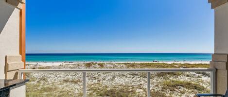 A balcony with a view of a beach and ocean.