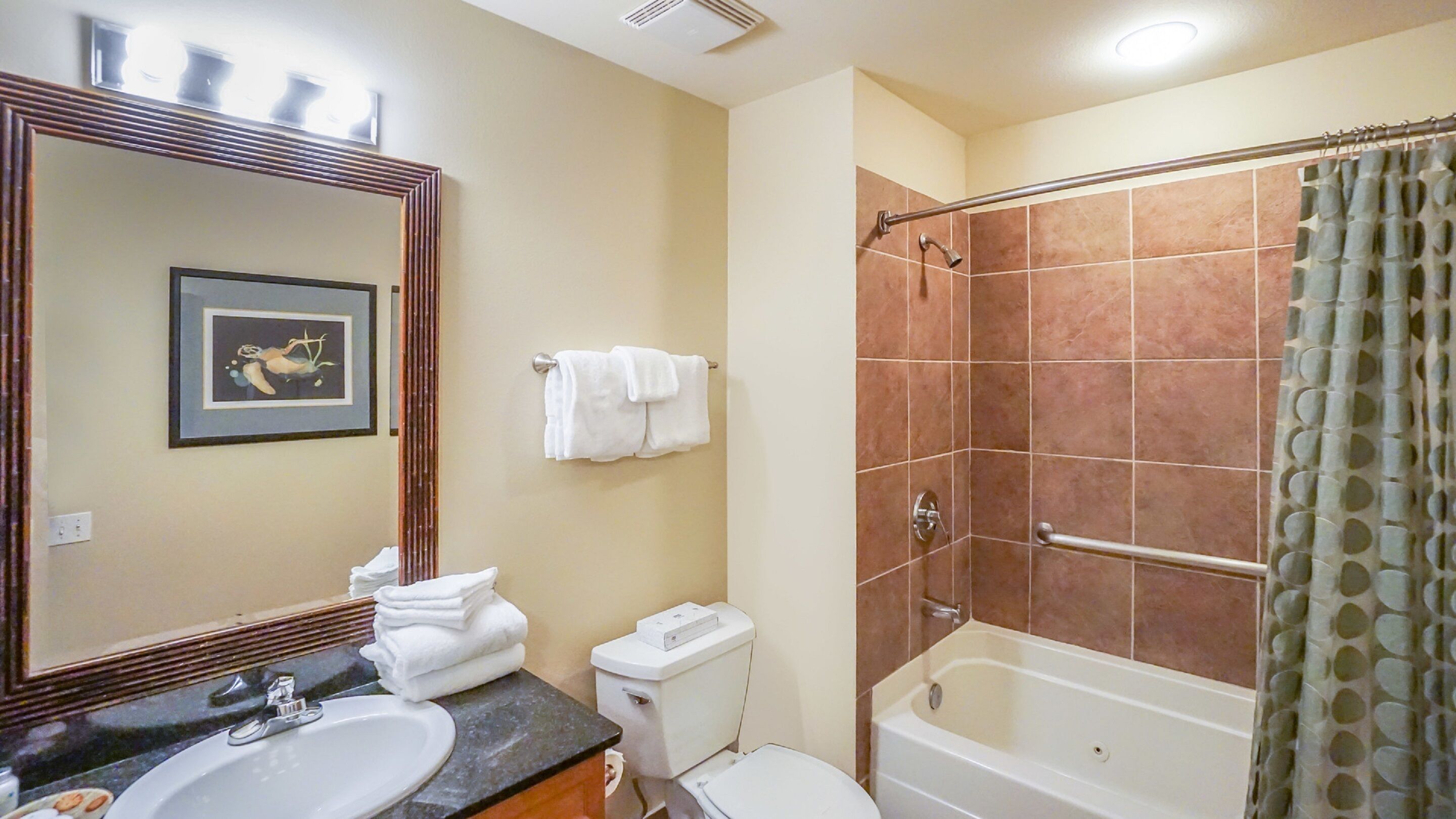 Un baño con lavamanos, espejo, inodoro y ducha.