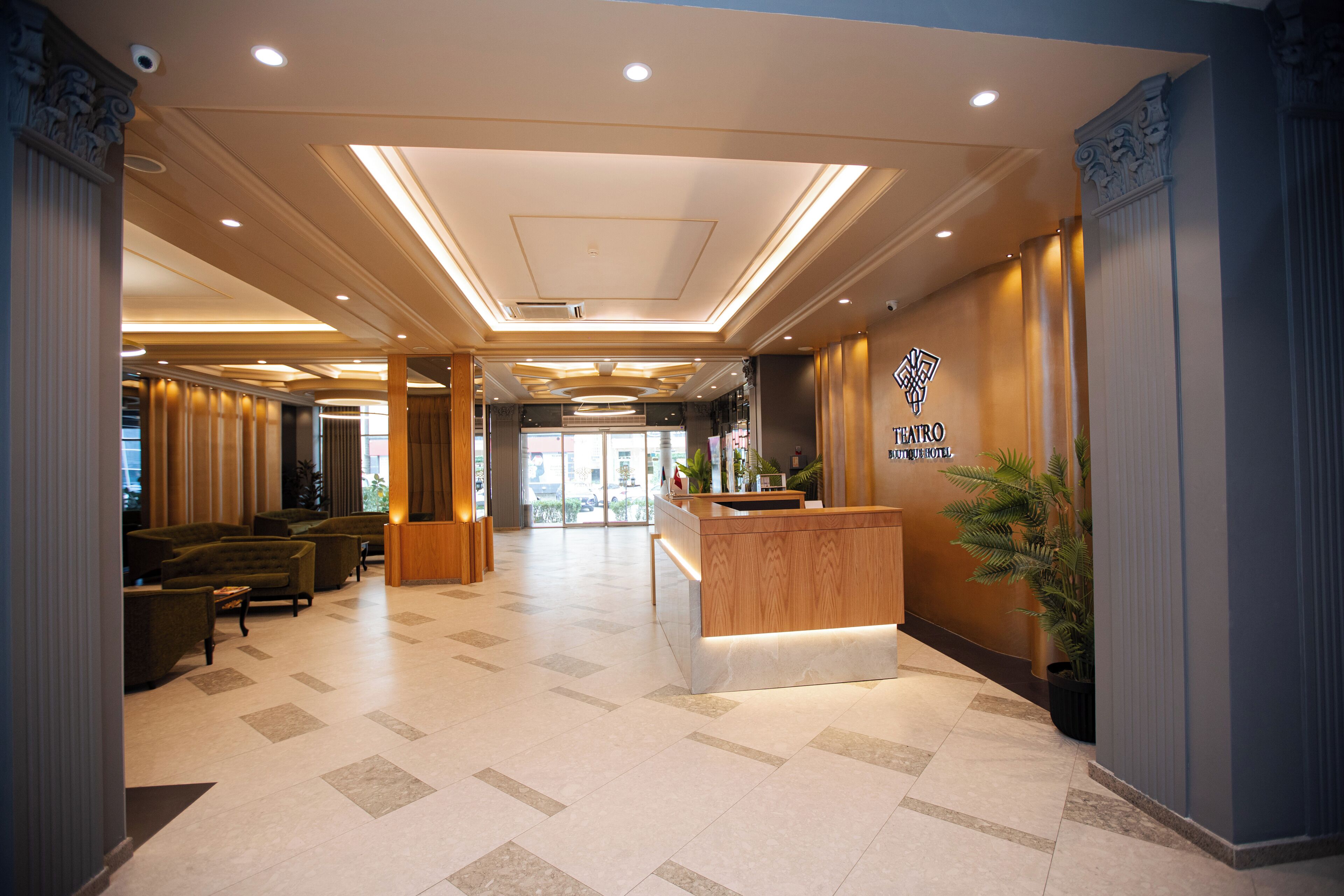 A hotel lobby with a reception desk, seating area, and a view of the entrance.