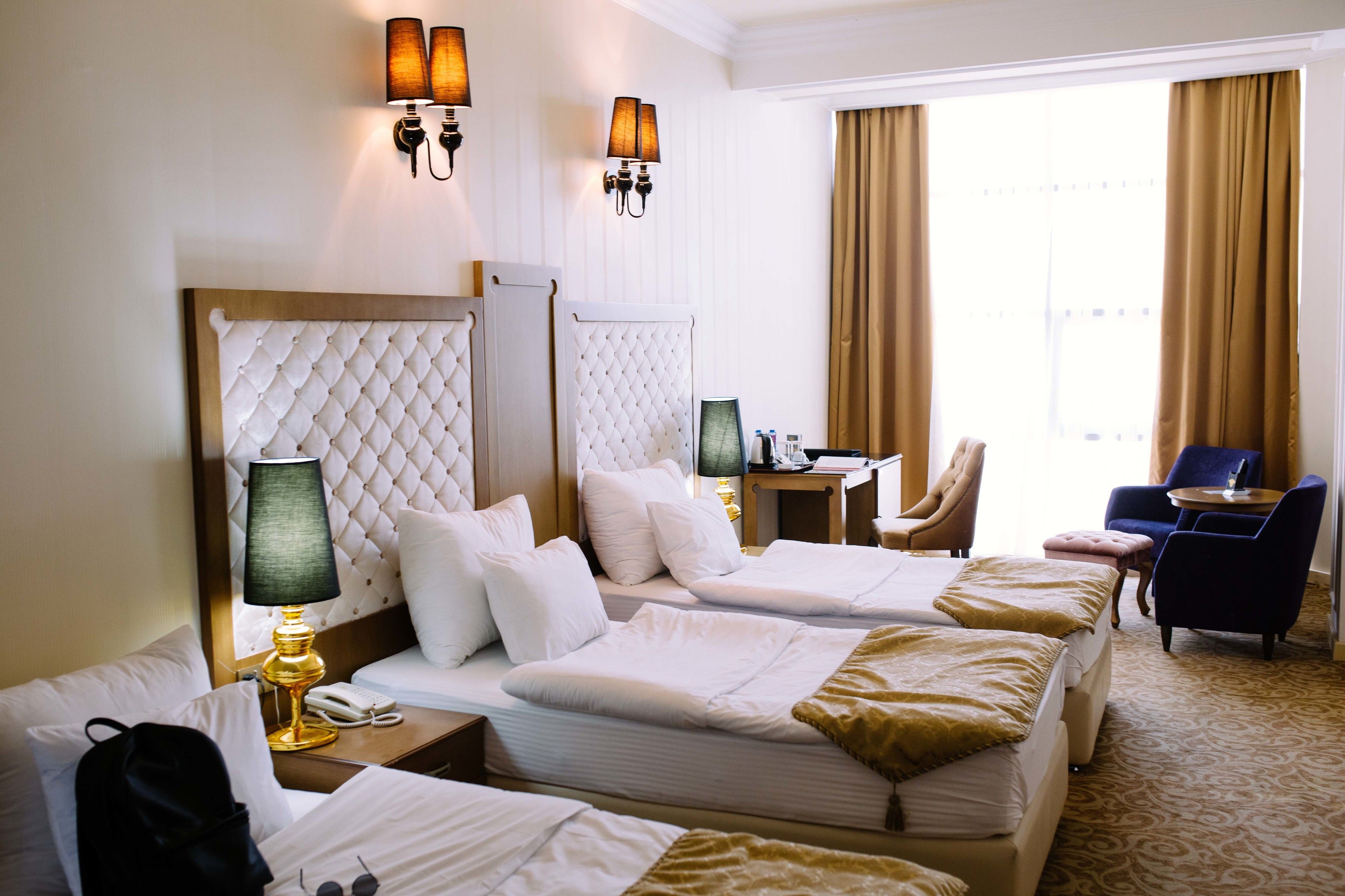 A hotel room with two beds, a desk, a chair, and a view of the city.