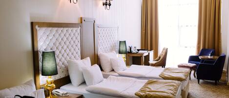 A hotel room with two beds, a desk, a chair, and a view of the city.