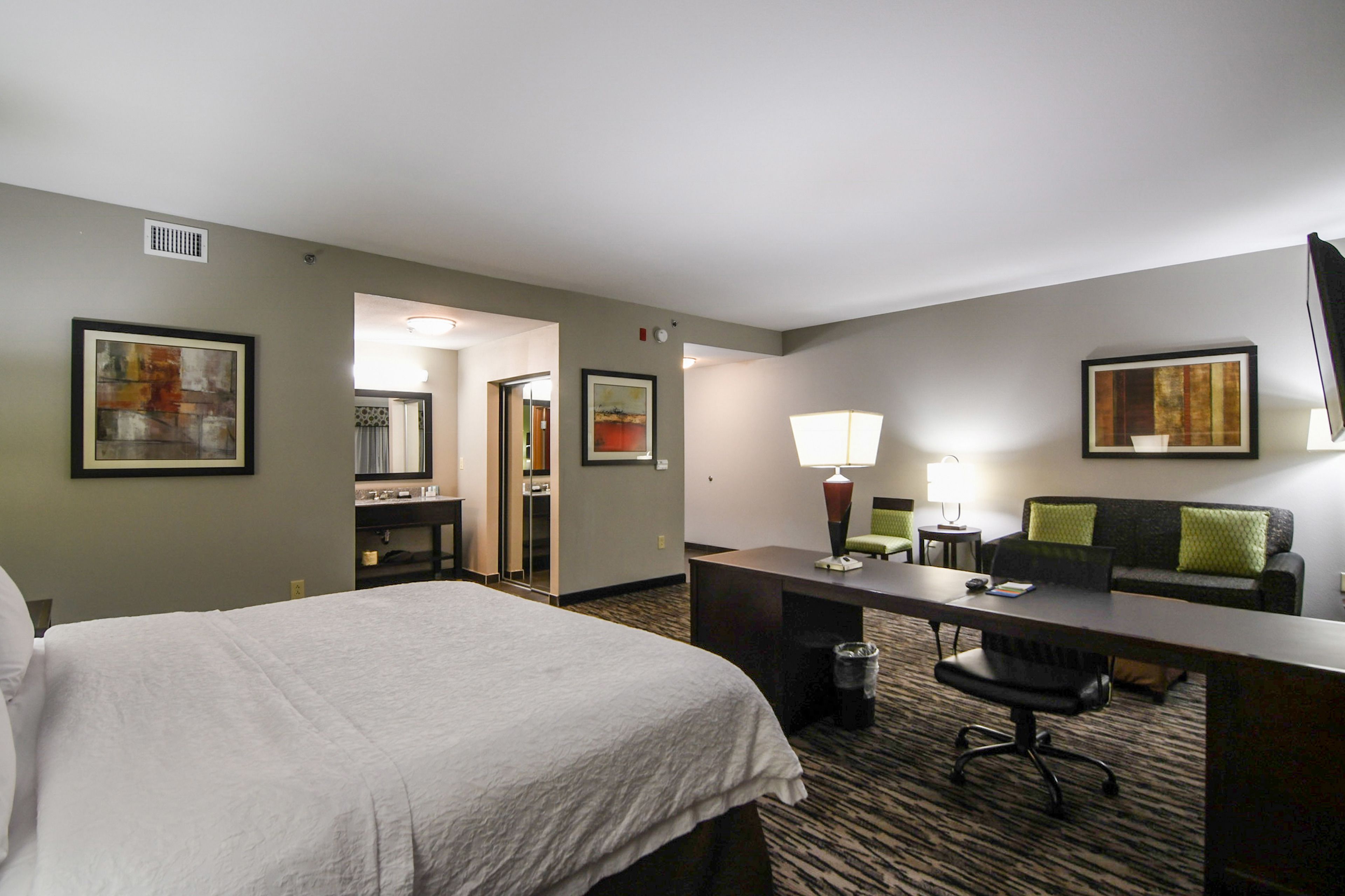 Ein Hotelzimmer mit Bett, Schreibtisch, Stuhl und einer Couch.