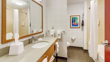 A bathroom with a large mirror, a sink, a toilet, and a shower.