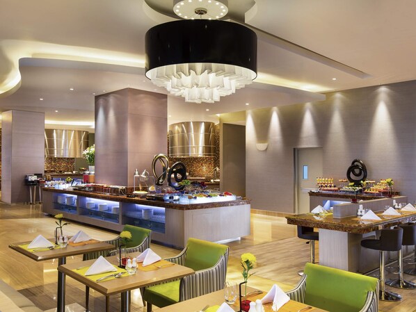 A modern hotel lobby with a central buffet, seating areas, and a stylish chandelier. - Novotel Tangerang (Tangerang)