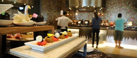 A dessert display with various cakes and pastries on a marble counter in a restaurant setting.