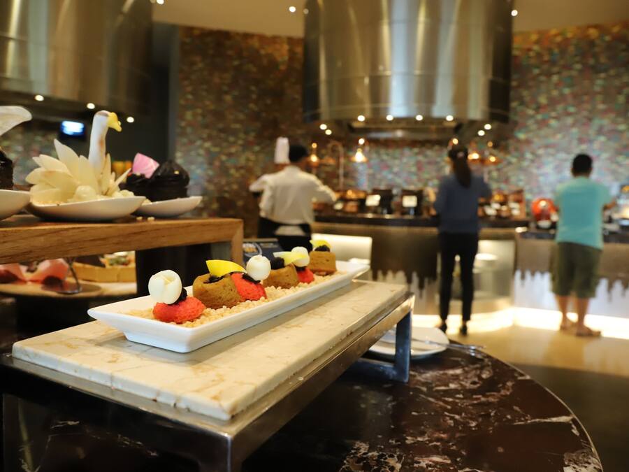 A dessert display with various cakes and pastries on a marble counter in a restaurant setting.