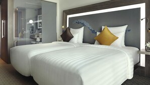 Quarto de hotel com duas camas, um espelho grande e uma mesa de cabeceira com abajur.