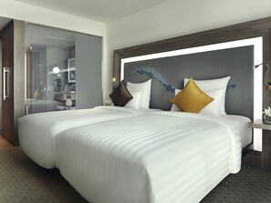 A hotel room with two beds, a large mirror, and a nightstand with a lamp. - Novotel Tangerang (Tangerang)