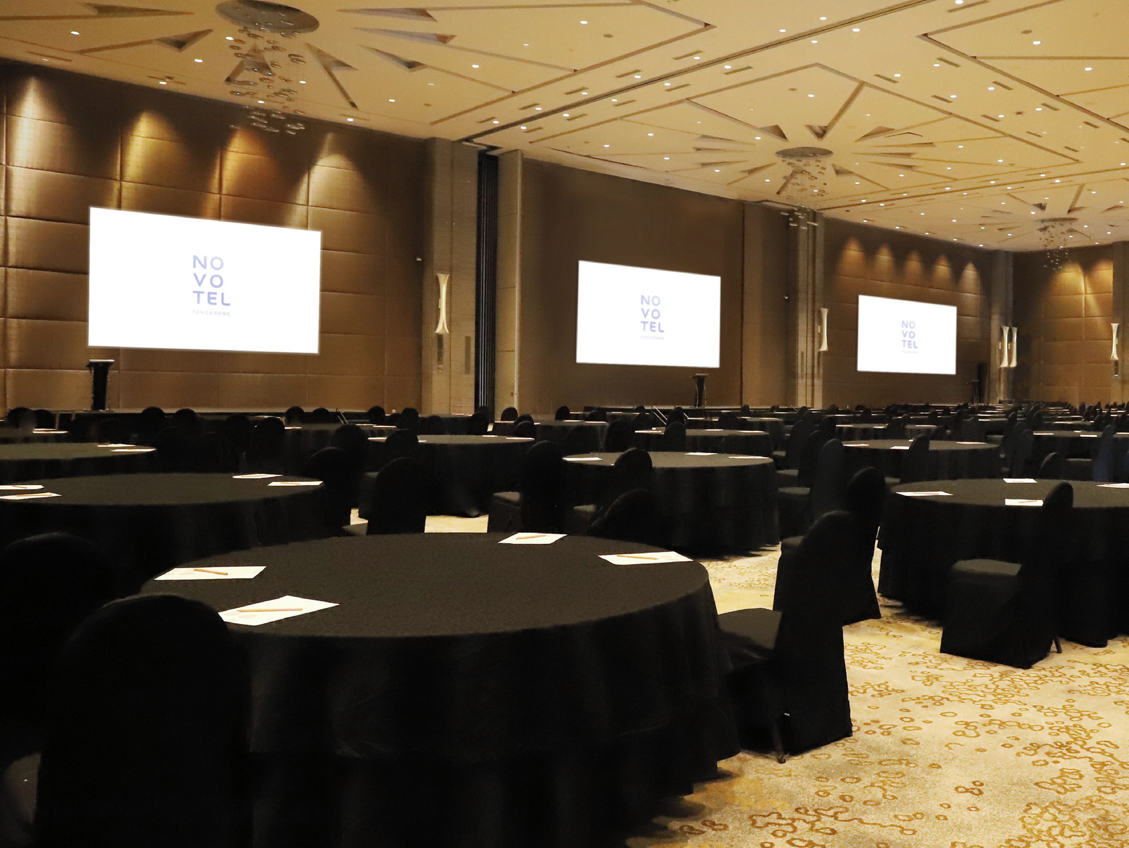 A conference room with multiple tables and chairs, equipped with projectors displaying 'NO VOTE TEL' on the screens.