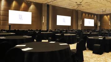 Uma sala de conferência com várias mesas e cadeiras, equipada com projetores exibindo 'NO VOTE TEL' nas telas.