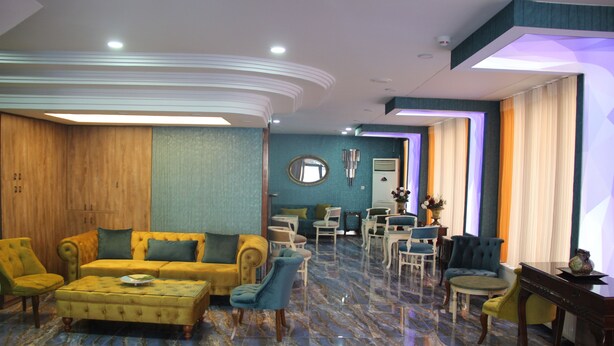 A spacious living area with a yellow sofa, blue armchairs, and a marble floor. - Kaya Madrid Hotel (Istanbul)