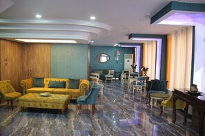 A spacious living area with a yellow sofa, blue armchairs, and a marble floor. - Kaya Madrid Hotel (Istanbul)