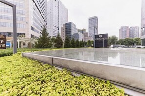 A modern urban plaza with a reflective water feature, surrounded by buildings and greenery. - Donghuang Kaili Hotel (Beijing)