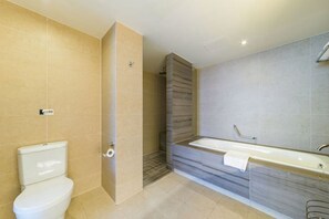 Et moderne badeværelse med toilet, bruser og et stort badekar.
