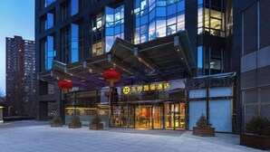 Un hotel moderno con facciata in vetro, area salotto esterna e lanterne rosse tradizionali.