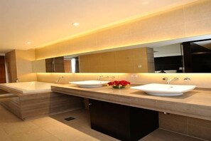 A modern bathroom with two sinks, a large mirror, and a vase of flowers. - Donghuang Kaili Hotel (Beijing)