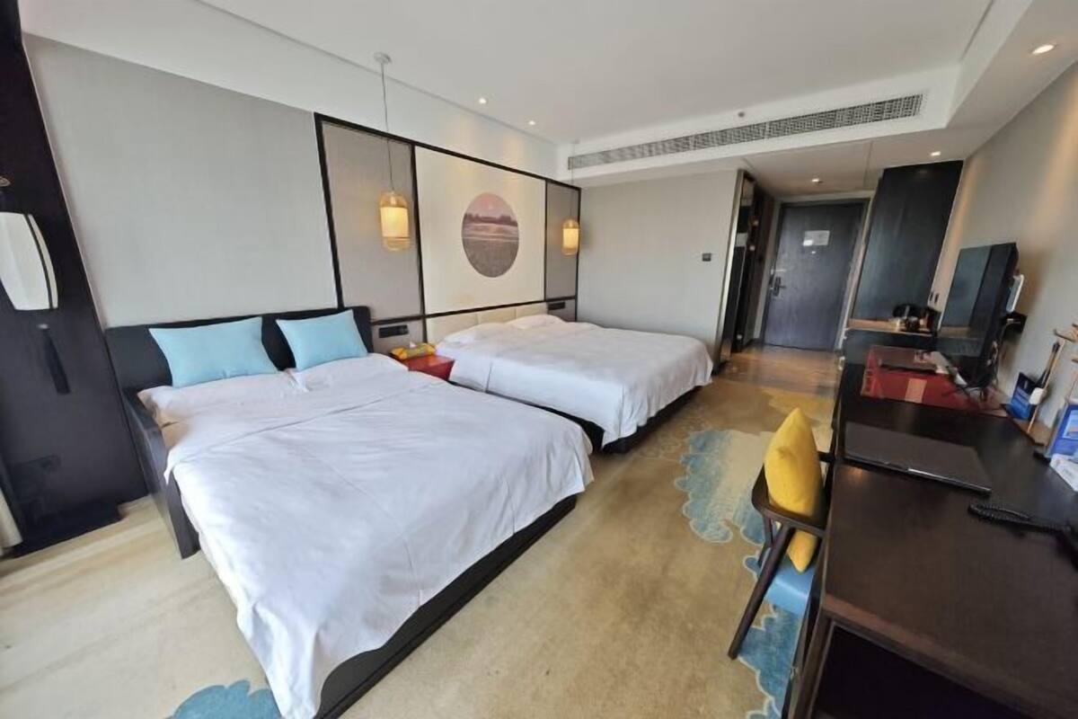 Ein Hotelzimmer mit zwei Betten, einem Schreibtisch und einem Stuhl.