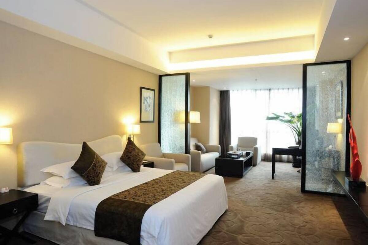 Ein Hotelzimmer mit einem großen Bett, zwei Nachttischen, einem Schreibtisch, einem Stuhl und einem Sofa.
