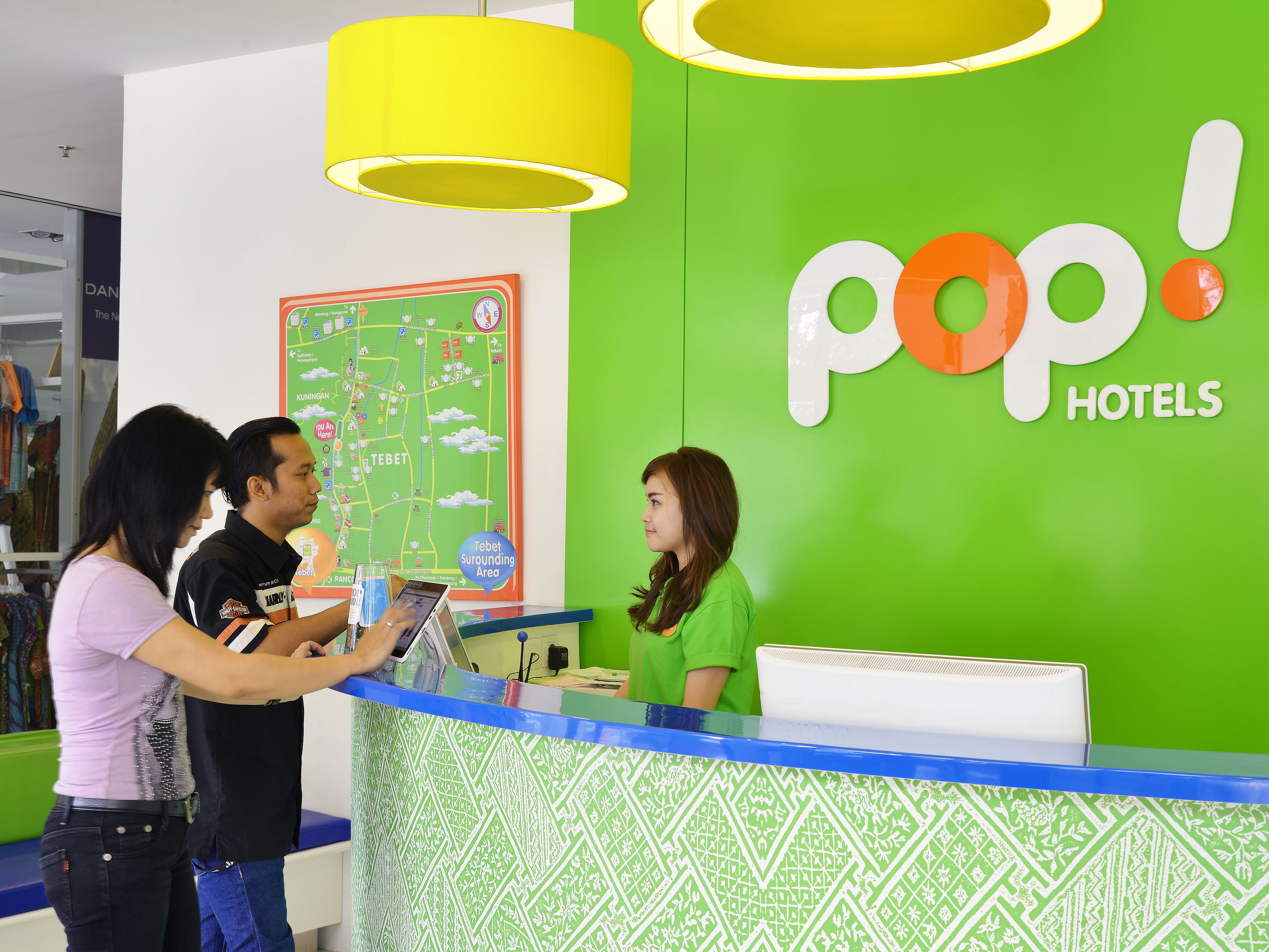 A hotel reception desk with a green wall and a map of the surrounding area.