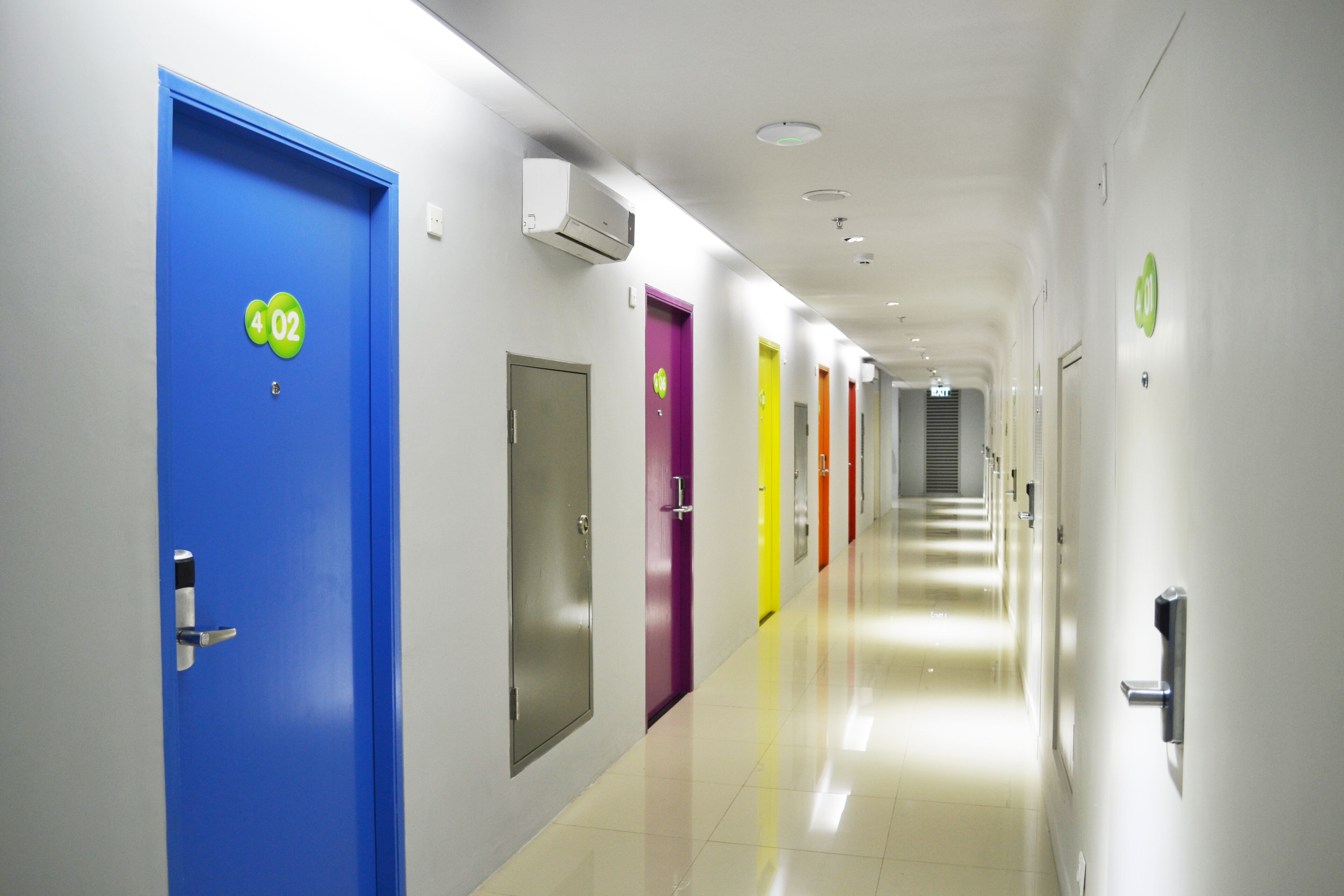 Een gang met deuren genummerd 4, 02 en 03, die naar kamers leiden.