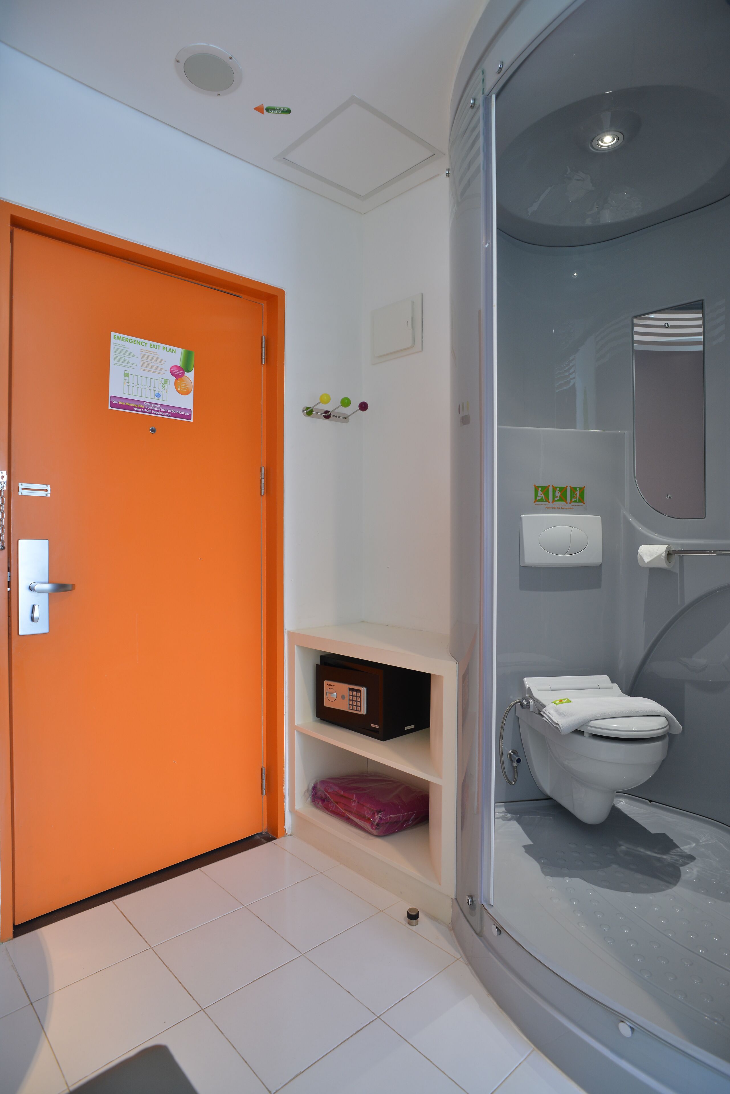 A bathroom with a glass-enclosed shower, an orange door, and a white toilet.