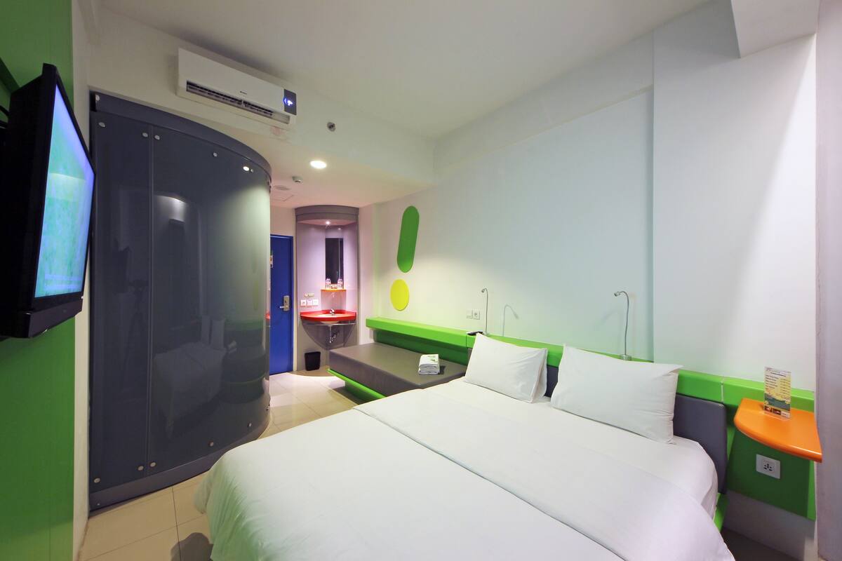 Een hotelkamer met een bed, een televisie, een badkamer met een wastafel en een douche.
