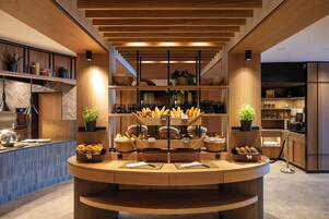 Una cocina moderna con armarios de madera, una isla central con cestas para pan y un salpicadero con estampado en espiga.
