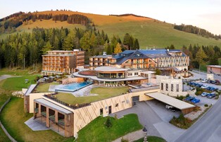 A modern hotel with multiple floors, a swimming pool, and a parking area.