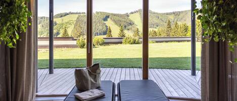 Una habitación con dos sillones reclinables frente a una vista panorámica de una ladera boscosa.