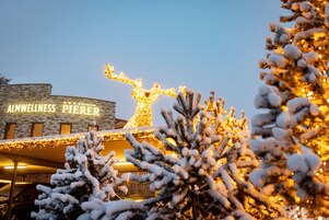 Un edificio con un letrero que dice "ALMWELLNESS PIERER" y un árbol de Navidad con luces en el frente.