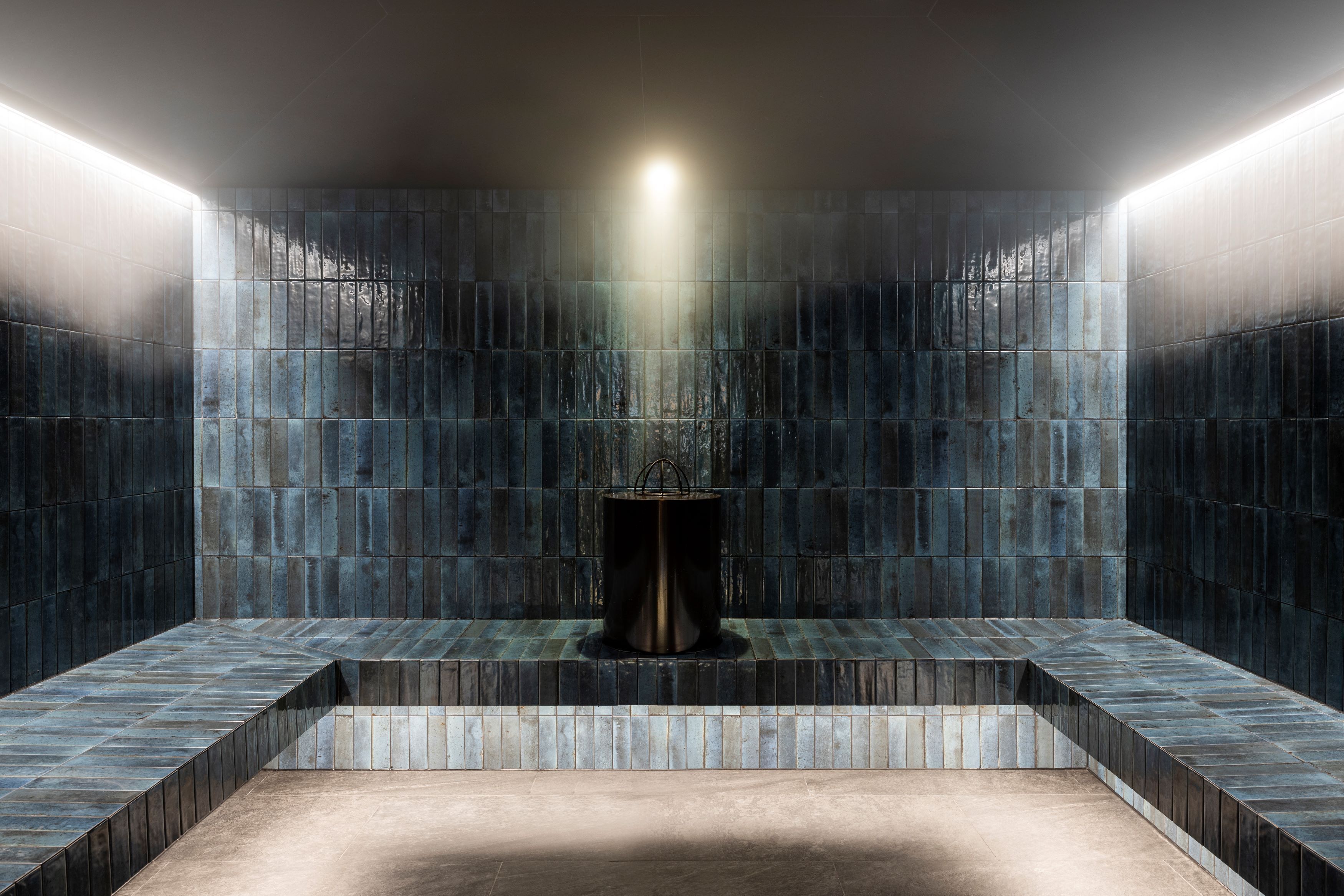 A modern bathroom with a central sink, tiled walls, and a bench.