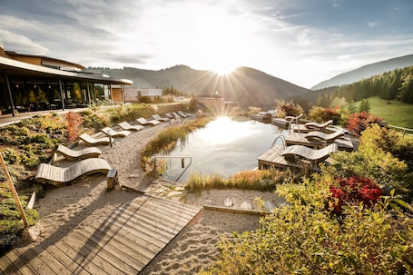 Innenpool, Außenpool, Sonnenschirme, Liegestühle. Almwellness Hotel Pierer