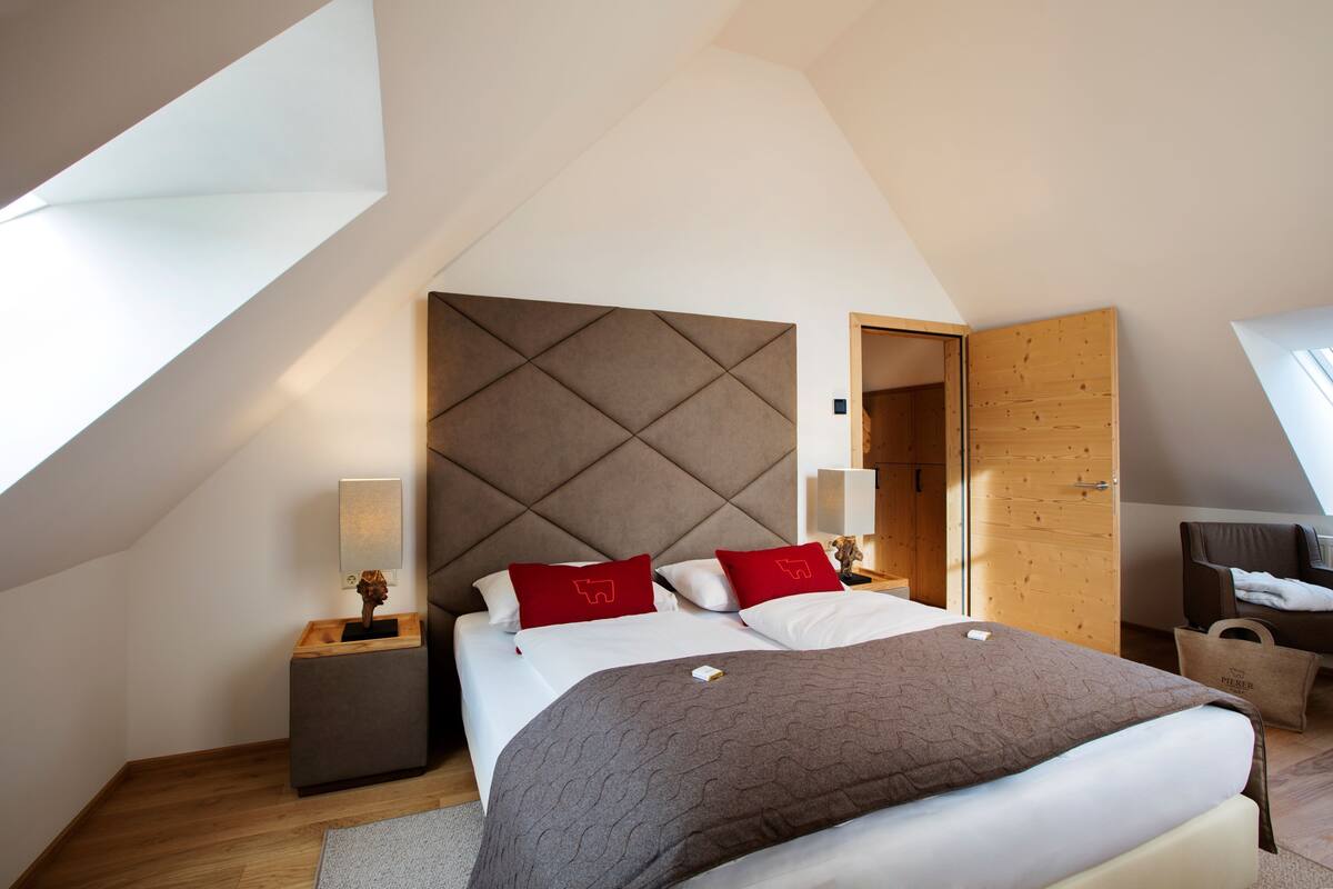 A modern bedroom with a large bed, a wooden headboard, and a skylight.