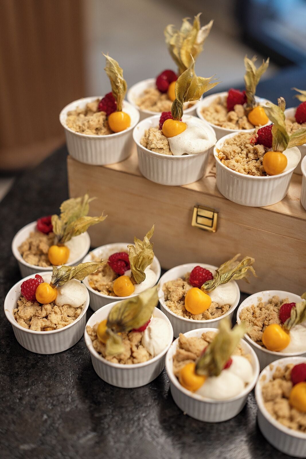 A series of dessert cups arranged on a wooden board.