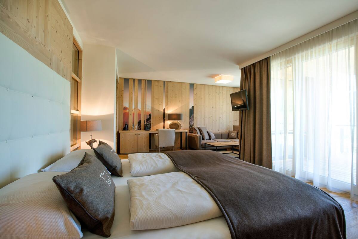 A hotel room with a large bed, a desk, a chair, and a TV.