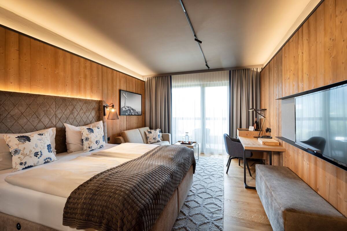 A modern hotel room with a large bed, a desk, and a TV.