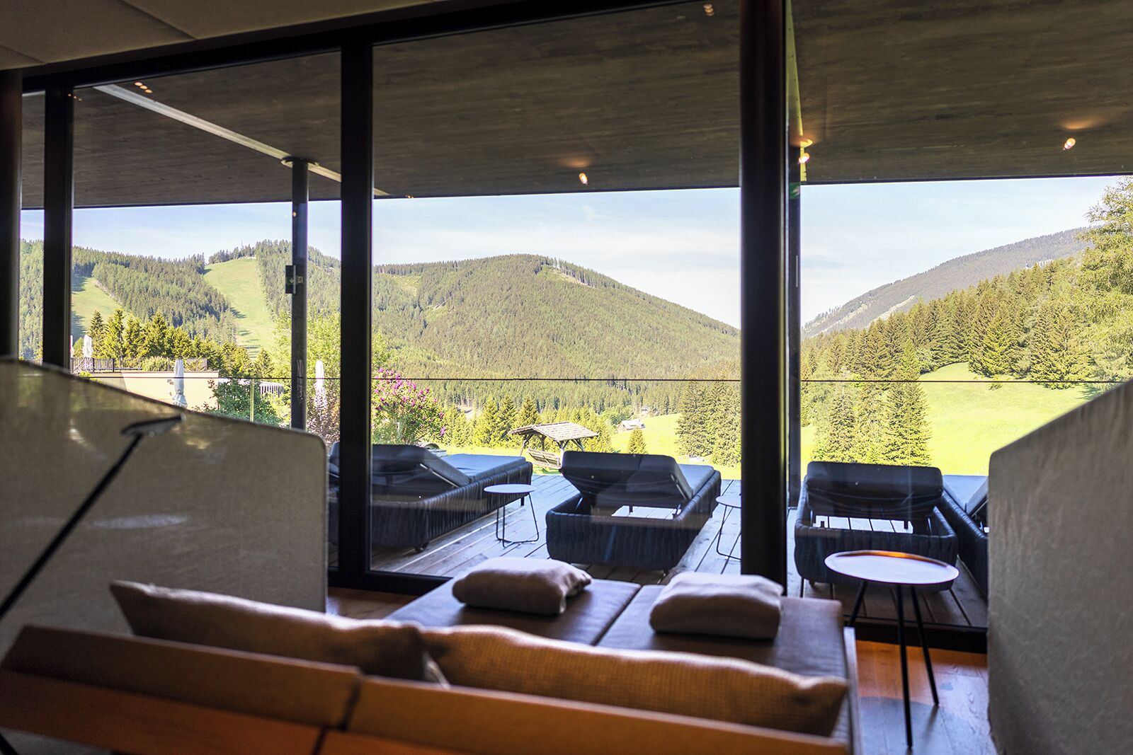 A modern interior with large windows offering a view of a mountainous landscape.