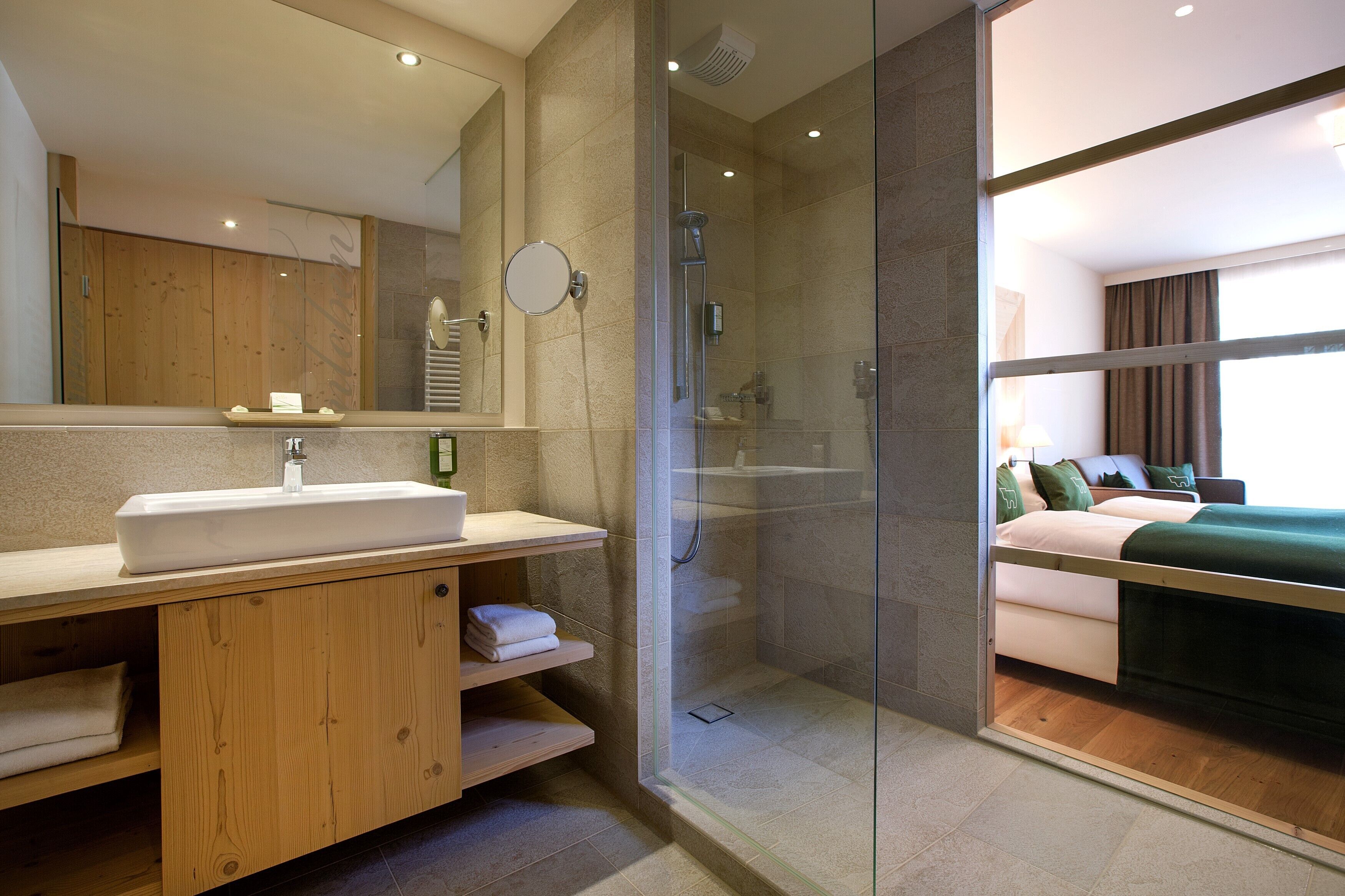 A modern bathroom with a large sink, mirror, and glass shower enclosure.