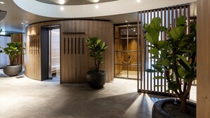 Un hall d’entrée moderne avec un plafond incurvé, des lambris en bois et de grandes plantes en pot.